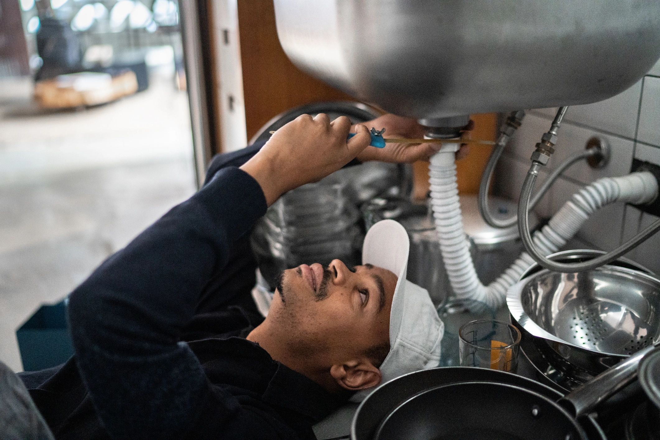 Plumber repairing pipes under a kitchen sink
