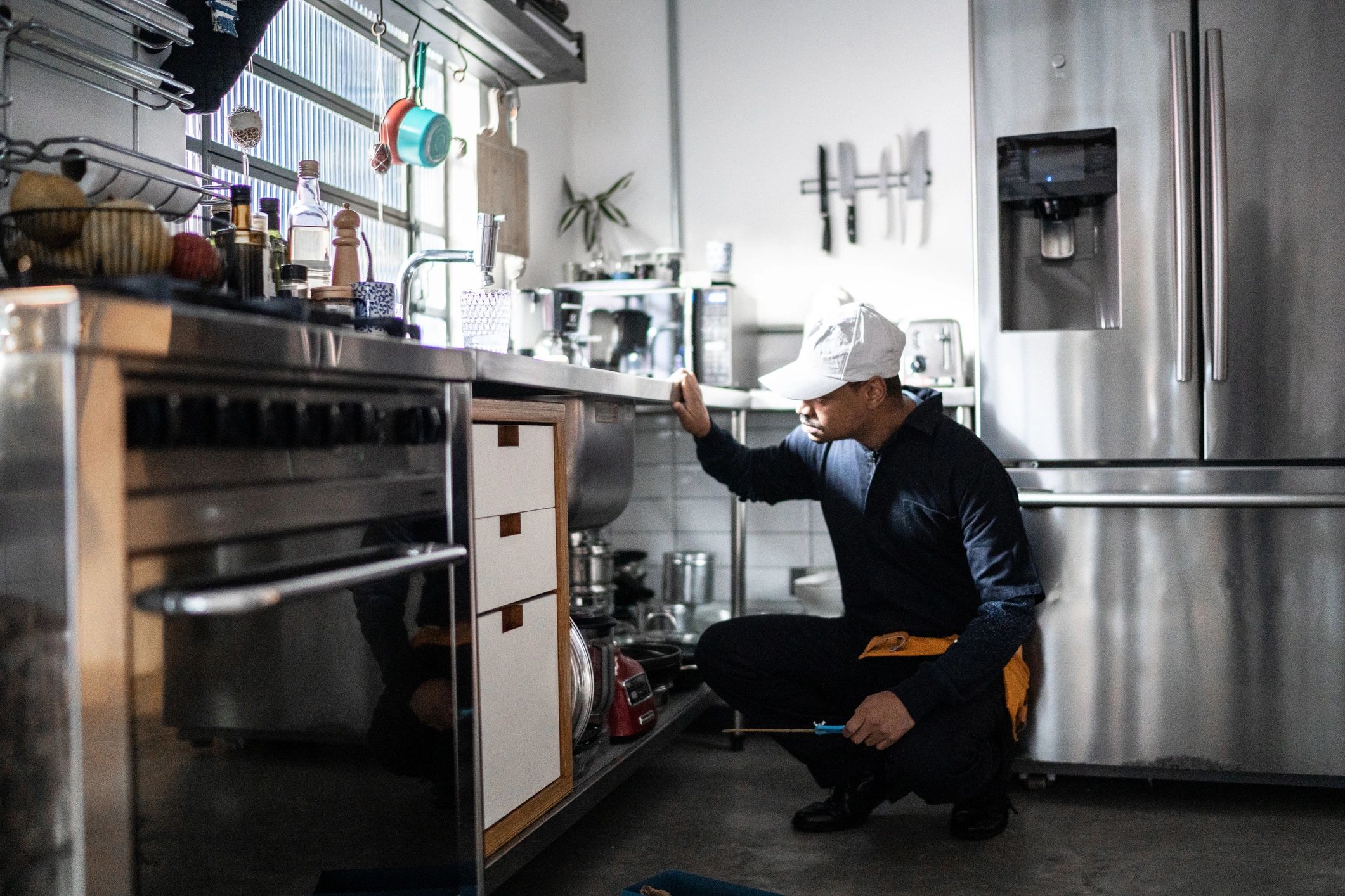 Plumber inspecting a kitchen sink during a service call
