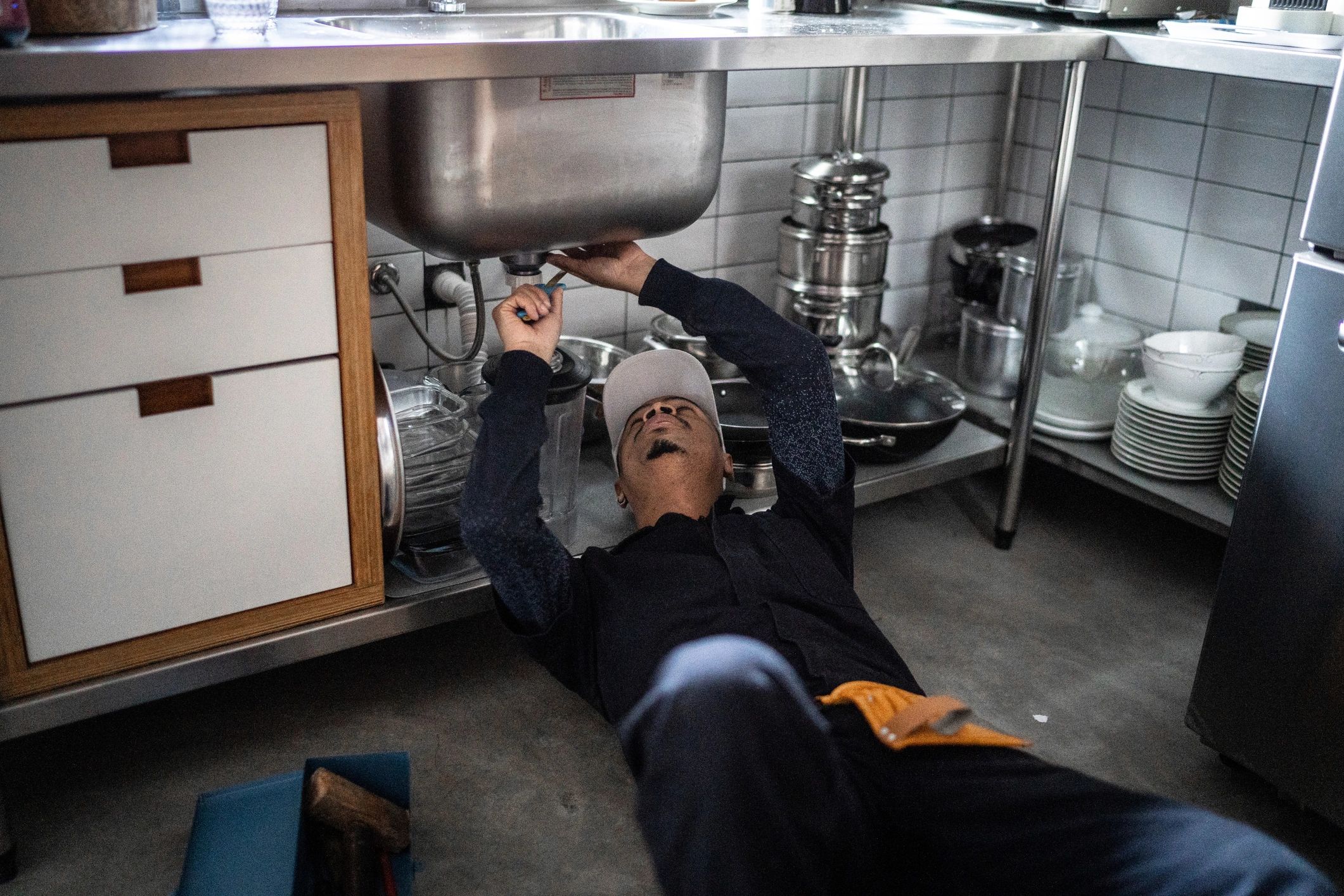 Plumber repairing plumbing under a sink