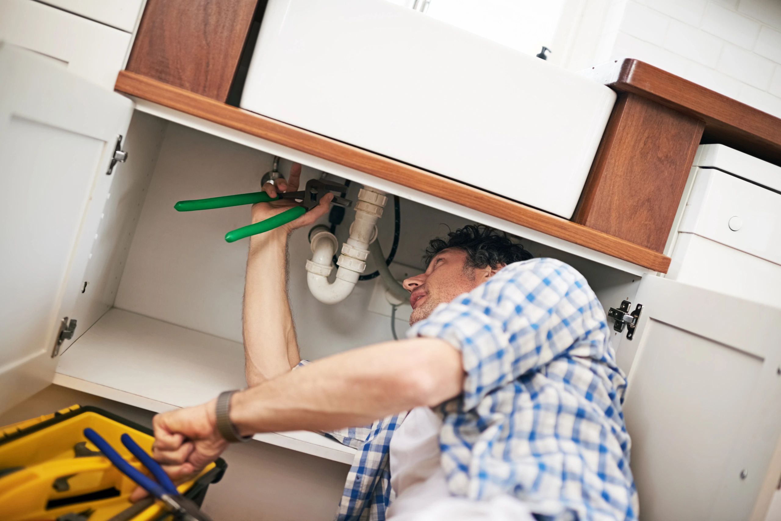 Plumber working under a sink